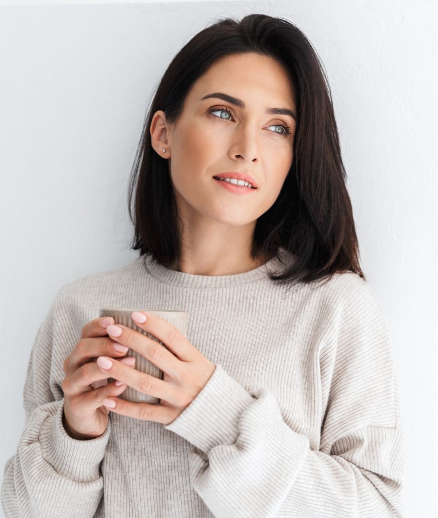 woman in white sweater holding a cup